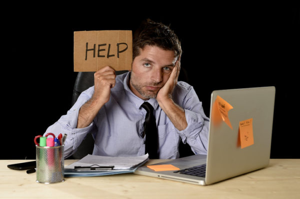 A man holding a help sign while sitting on laptop